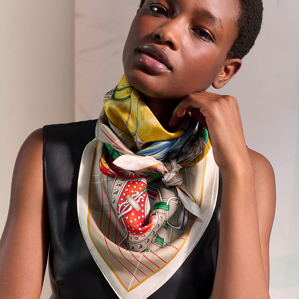 Model wearing a multicoloured Hermès Carré 90 silk scarf over a black top.