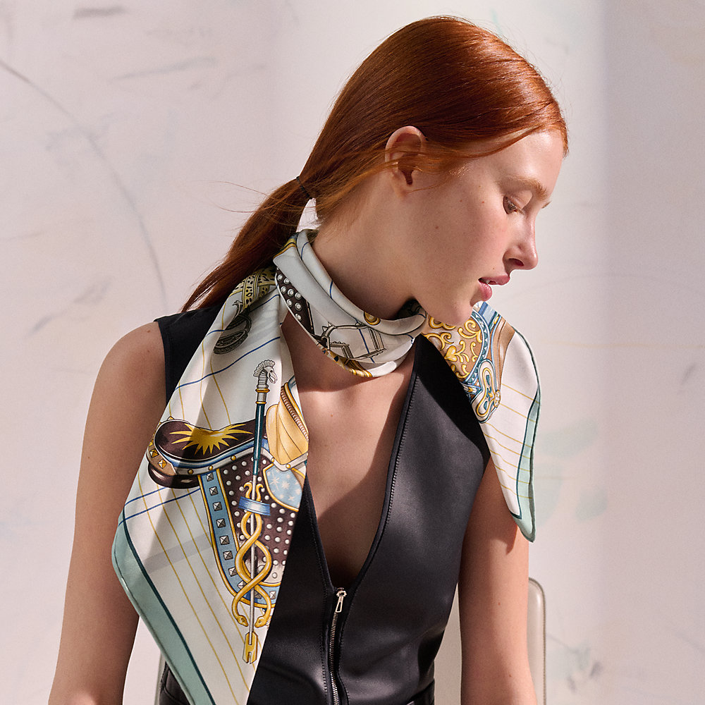 White Hermès Carré 90 silk scarf draped around a model’s neck.
